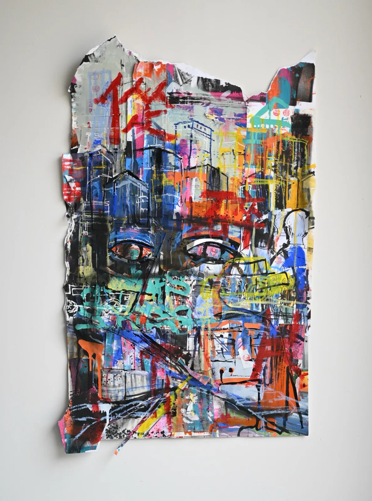 A torn-edge mixed-media portrait combining eyes, buildings, vehicles, and colorful marks
